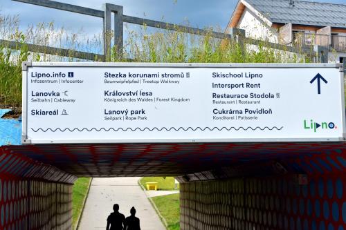 a sign over a bridge with people walking under it at Family home Lipno Lake, Airstay Lipno in Lipno nad Vltavou