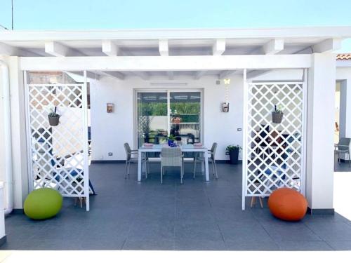 eine weiße Terrasse mit einem Tisch und Stühlen sowie einem Tisch und einem Chairsktop in der Unterkunft Villa White Sicilia in Santa Maria Del Focallo