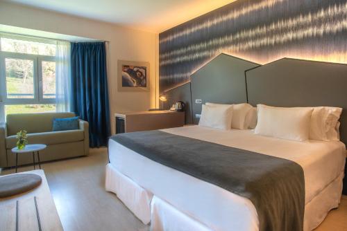 a hotel room with a large bed and a chair at Barceló Costa Vasca in Donostia-San Sebastián