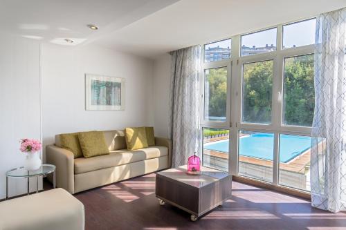a living room with a couch and a large window at Barceló Costa Vasca in Donostia-San Sebastián