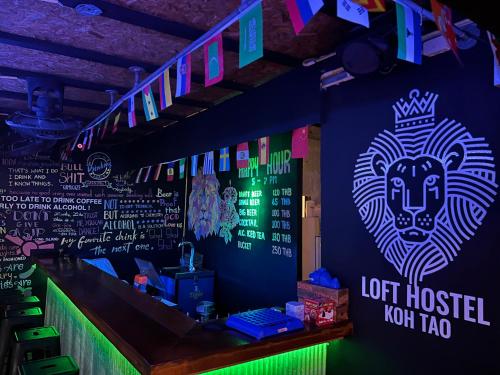 un bar con una cabeza de león encendida en la pared en Loft Hostel Koh Tao en Ko Tao