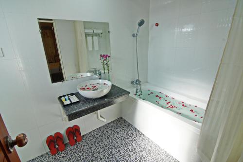 bagno con lavandino e vasca con specchio di Royal Pearl Hotel a Mandalay