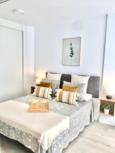 a white bedroom with a bed with pillows at Castro Holidays - Apto A Céntrico Terraza con Garaje Gratis in Castro-Urdiales