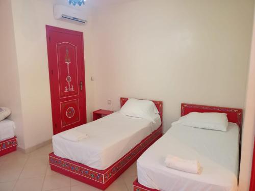 a bedroom with two beds and a red door at Dar Bouanani in Asilah