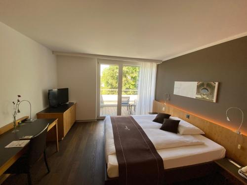 una camera con letto, scrivania e TV di Hotel & Restaurant STERNEN MURI bei Bern a Berna