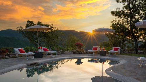 a pool with chairs and umbrellas and a sunset at TERRIPI 10, Emma Villas in Pomarance