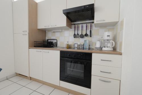 une cuisine avec des armoires blanches et un four noir dans l'établissement 200m plage des Demoiselles- Appartement pour 4, à Plage-des-Demoiselles