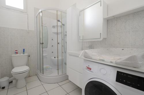 une salle de bain blanche avec toilettes et douche dans l'établissement 200m plage des Demoiselles- Appartement pour 4, à Plage-des-Demoiselles