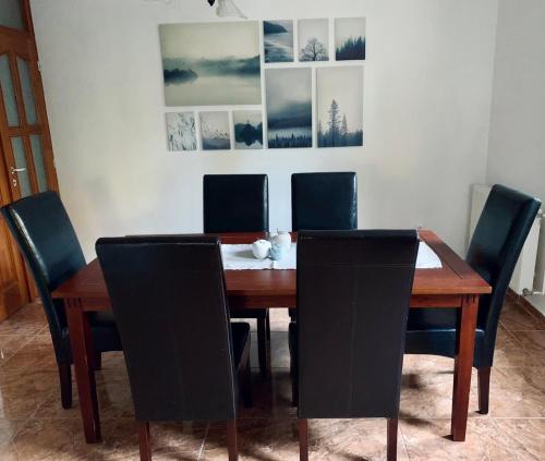 a dining room table and chairs with pictures on the wall at Small Lake Apartman in Esztergom