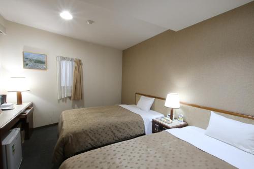 een hotelkamer met 2 bedden en 2 lampen bij Hotel Aston Hotel Osaka Sakai in Sakai