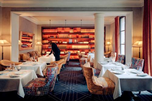 ein Restaurant mit Tischen und Stühlen und eine Person, die in einem Zimmer steht in der Unterkunft Le Pavillon de la Reine & Spa in Paris