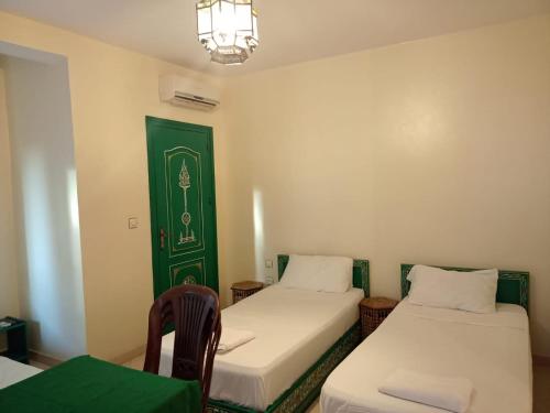 a room with two beds and a green door at Dar Bouanani in Asilah