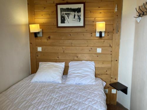 a bedroom with a wooden wall with a bed with two pillows at Appartement Avoriaz, 2 pièces, 4 personnes - FR-1-634-79 in Morzine