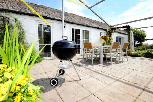 a grill on a patio with a table and chairs at Craigadam Lodge with Hot tub in Castle Douglas