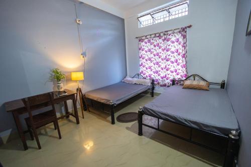 una camera con due letti e un tavolo e una finestra di Samay Homestay a Dibrugarh
