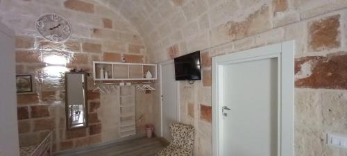 a room with a stone wall with a door and a clock at 30 METRI QUADRATI in Monopoli