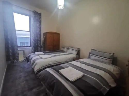 two beds in a room with a window at Lovely one bedroom Apartment in Glasgow City in Glasgow