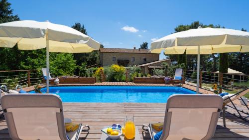 a swimming pool with two chairs and two umbrellas at Masso delle Fanciulle 14, Emma Villas in Pomarance
