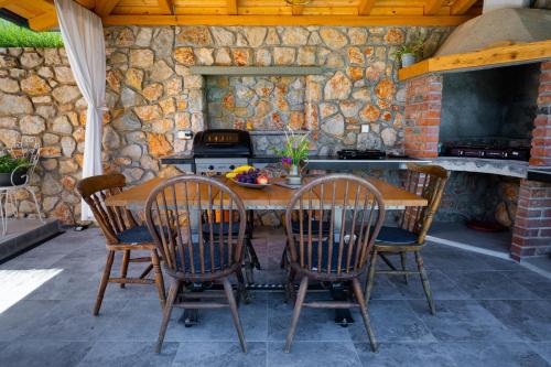 eine Außenküche mit einem Holztisch und Stühlen in der Unterkunft Ferienhaus Nera in Plomin