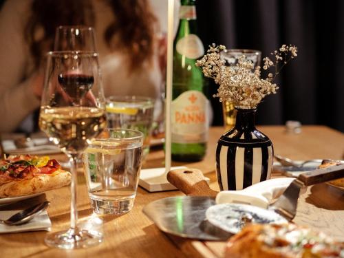 a wooden table with a bottle of wine and a pizza at aletto Hotel Potsdamer Platz in Berlin