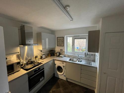 a kitchen with a sink and a washing machine at Bow House - SleepyLodge in London