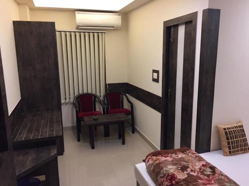 シリグリにあるAtithi Guest Houseの椅子2脚、ベッド1台、ピアノが備わる客室です。