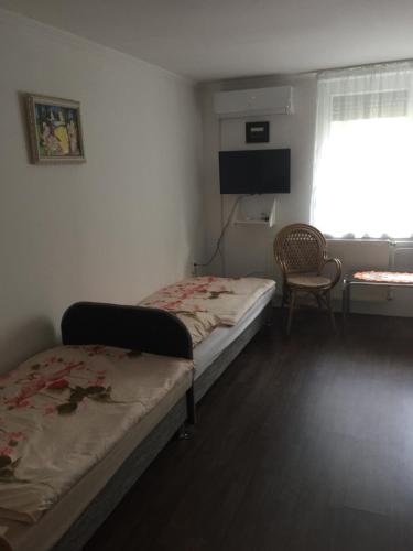 een slaapkamer met 2 bedden, een raam en een stoel bij Betty apartman in Nyíregyháza