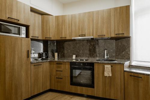 a kitchen with wooden cabinets and a sink and a microwave at Senator Maidan in Kyiv