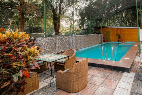 - une piscine avec une table et des chaises dans le jardin dans l'établissement Hotel Raj Resort, à Madgaon