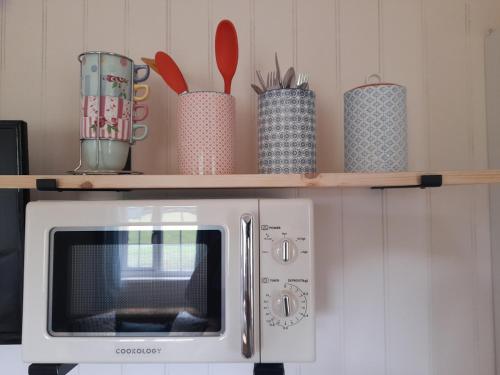 a microwave on a shelf with utensils on it at Dinky's Den in Coverack
