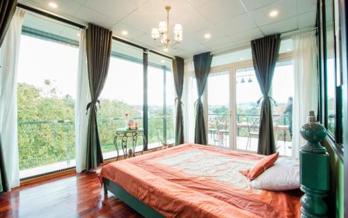 a bedroom with a large bed and large windows at Dalat Terrasse Des Roses Villa in Da Lat