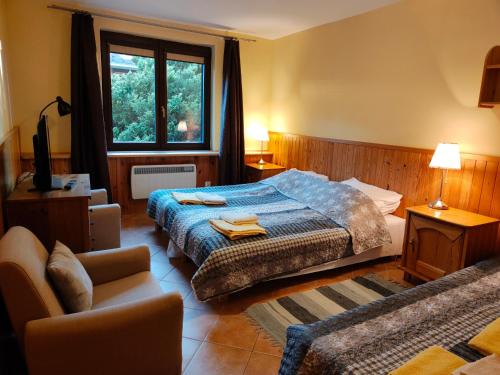 a bedroom with a bed and a chair and a window at Apartamenty Kotwica in Poddąbie