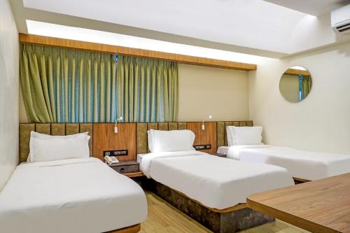 a hotel room with two beds and a table at Hotel Olten in Mumbai