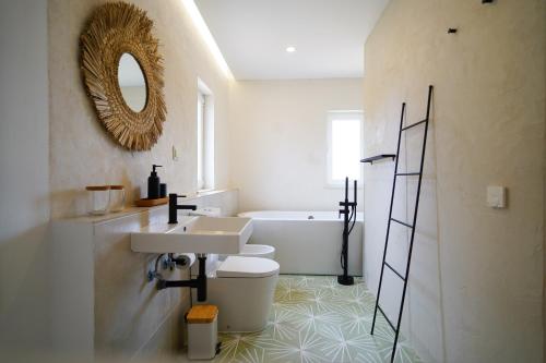 ein Badezimmer mit einem Waschbecken, einem WC und einer Badewanne in der Unterkunft Birds of Paradise in Aljezur