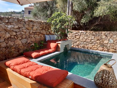 una piscina con almohadas rojas junto a una pared de piedra en Maison 2 chambres et piscine chauffée entre L'Ile Rousse et Monticello, en Monticello