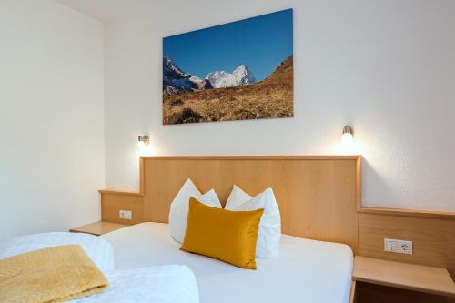 a bedroom with a bed with a yellow pillow at Apart Garni Astrada in Kappl