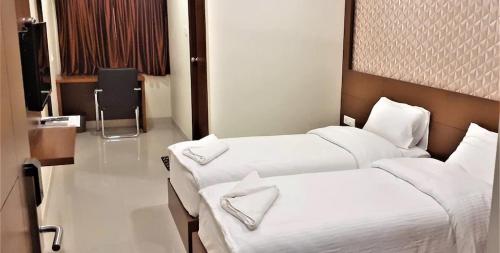 a hotel room with two beds and a chair at A and M Rooms and Residences in Chennai