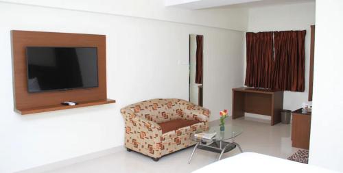 a living room with a chair and a television at A and M Rooms and Residences in Chennai
