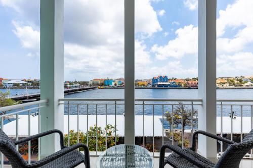 a balcony with chairs and a view of the water at Blue Marlin Handelskade Apartments in Willemstad