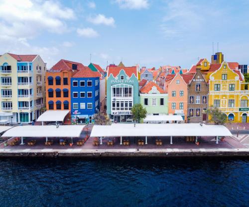 a group of colorful buildings next to a body of water at Blue Marlin Handelskade Apartments in Willemstad