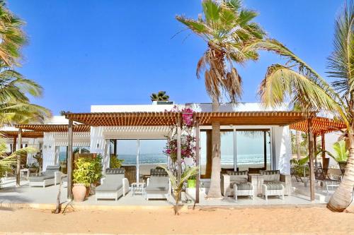 un complejo con sillas blancas y palmeras en la playa en Villa Cristina Alojamento, Praia de Chaves, Boa Vista, Cape Verde, WI-FI en Sal Rei