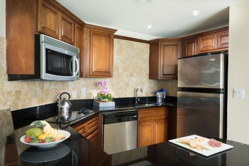 a kitchen with wooden cabinets and stainless steel appliances at Divi Aruba Phoenix Beach Resort in Palm-Eagle Beach