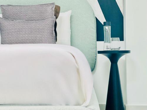 1 dormitorio con cama blanca y cabecero azul en Canaryislandshost l Boya Suites, en Playa Honda