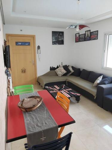 a living room with a table and a couch at Appartement 1ch Romantique Vue sur Piscine in Nabeul