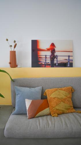 a gray couch with pillows and a picture of a woman at Birds of Paradise - Boutique Surf Lodge in Aljezur