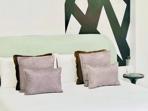 a white bed with three pillows and a large letter k at Canaryislandshost l Boya Suites in Playa Honda