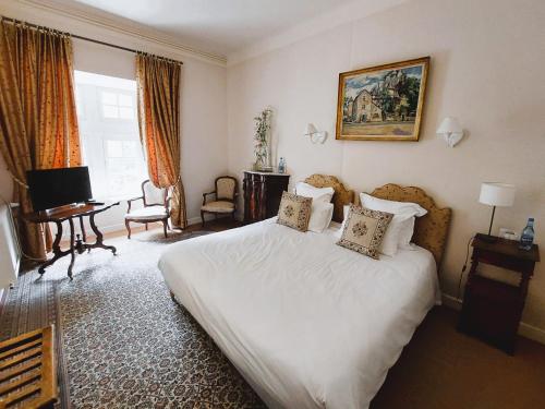 a bedroom with a large white bed and a desk at Hôtel-Restaurant Le Manoir De Montesquiou in La Malène