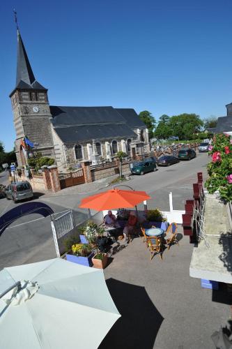 una strada con tavoli e ombrelloni e una chiesa di Hotel bar Saint Christophe a Le Tilleul