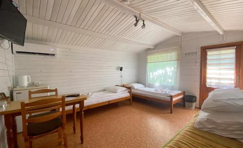 a room with two beds and a desk and a table at Olle Holiday house in Ventspils