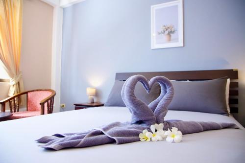 a towel shaped like two swans sitting on a bed at GOLDEN GUESTHOUSE by The Beach Cha Am in Cha Am